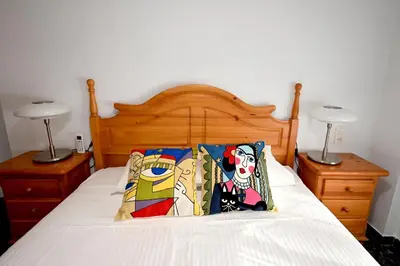 a bedroom with a bed with a wooden headboard and two lamps at EMMA Apartment in Puerto de Sagunto