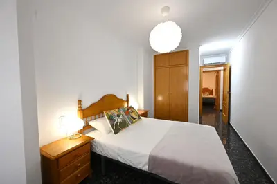 a bedroom with a white bed and a wooden cabinet at EMMA Apartment in Puerto de Sagunto
