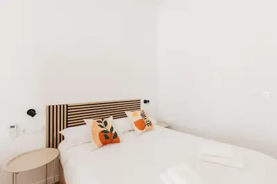 a white bedroom with a bed and a table at Stylish Studio with Easy Access to Valencias Best in Valencia
