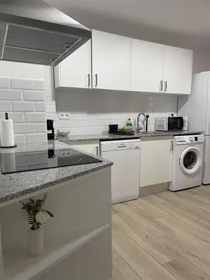 a kitchen with white cabinets and a washer and dryer at Little Rose apartment in Godella