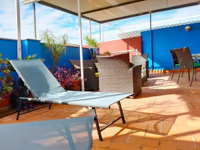 a patio with chairs and tables on a roof at Global Vacacional, Ático con barbacoa y gran terraza in Canet de Berenguer