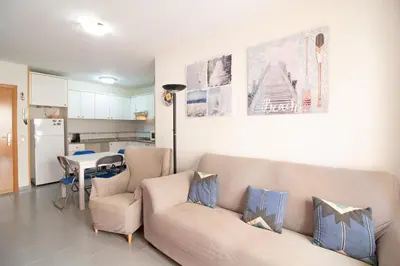 a living room with a couch and a table and a kitchen at Global Vacacional, Ático con barbacoa y gran terraza in Canet de Berenguer