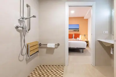 a bathroom with a shower and a sink and a bed at Apartamentos Sol de Azahar in Valencia