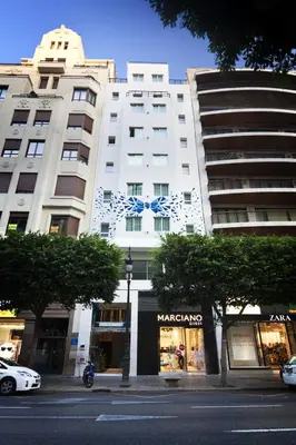a white building with a blue bow on it at One Shot Colón in Valencia