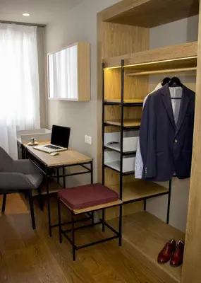 a room with a desk and a bed with a laptop at One Shot Colón in Valencia