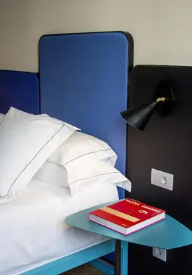a red book on a blue table next to a bed at One Shot Colón in Valencia