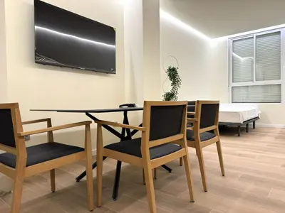 a dining room with a table and chairs with a tv on the wall at Suite Palacio Congresos in Valencia