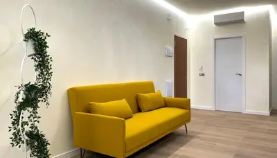 a yellow couch in a room with a door at Suite Palacio Congresos in Valencia