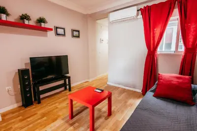 a living room with a red stool and a television at Queen Apt, 2min to Beach, Terrace, 3BD, 6PAX in Valencia