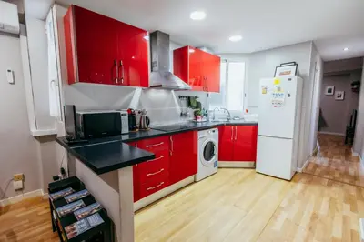 a kitchen with red cabinets and a white refrigerator at Queen Apt, 2min to Beach, Terrace, 3BD, 6PAX in Valencia