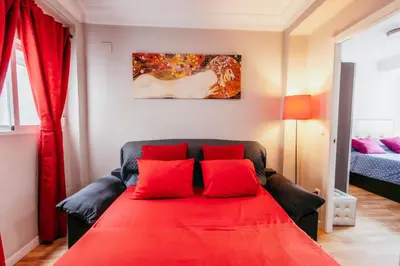 a red couch with two red pillows in a room at Queen Apt, 2min to Beach, Terrace, 3BD, 6PAX in Valencia