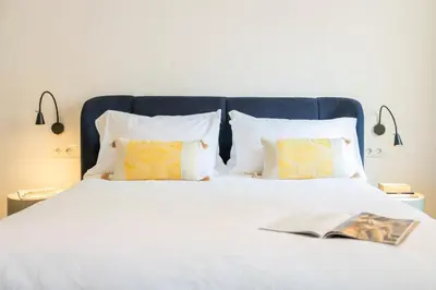 a white bed with two pillows and a book on it at Luxury new apartment 10 min walk to the beach, Late Checkout in Valencia