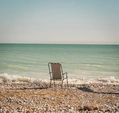 a chair sitting on a beach near the ocean at La Luz de Lucia in Moncófar