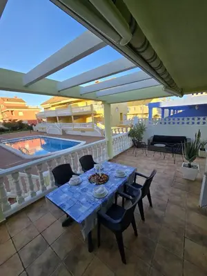 a patio with a table and chairs and a pool at Relax en familia junto al mar Les Palmeres in Sueca