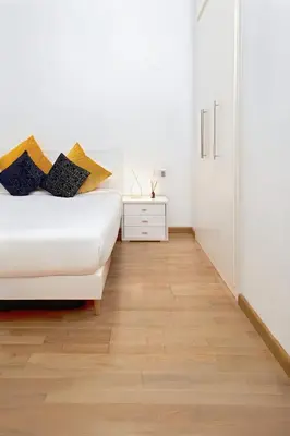 a bedroom with a white bed and a wooden floor at Grand Central Market Suites By VALENCIAFLATS EU in Valencia