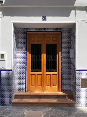 a wooden door on a house with blue and white tiles at Charming fisherman's house Cabanyal Cabañal in Valencia