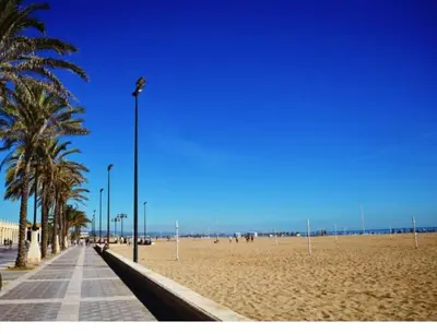 a sandy beach with palm trees and a street light at Charming fisherman's house Cabanyal Cabañal in Valencia