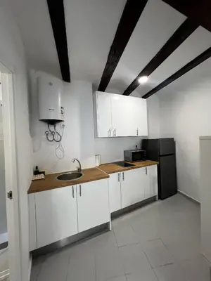 a kitchen with white cabinets and a black refrigerator at Piso 1 - Apartamento Mercado Central in Valencia