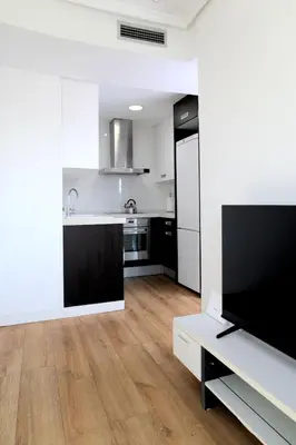 a kitchen with white walls and a flat screen tv at Resort & Suites Ciudad de las Ciencias By VALENCIAFLATS EU in Valencia