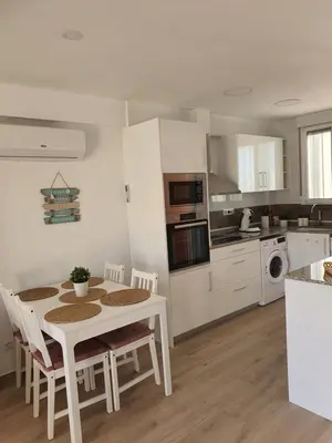 a white kitchen with a table and chairs in it at Edificio JUNIOR in Cullera