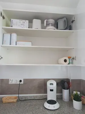 a kitchen counter with white shelves with a foodenser at Edificio JUNIOR in Cullera