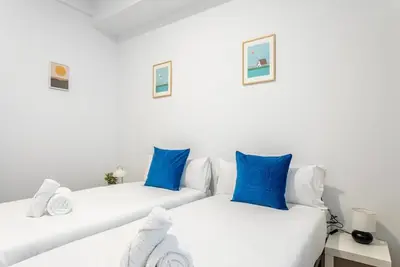 two beds in a white room with blue pillows at Balandra, Lovely flat close to center in Valencia