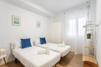 two beds in a white room with blue pillows at Balandra, Lovely flat close to center in Valencia