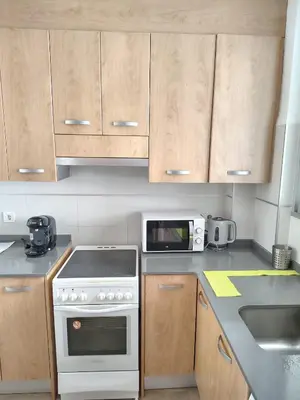 a kitchen with wooden cabinets and a white stove top oven at Agui House in Valencia