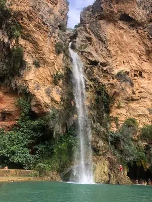 a waterfall on the side of a mountain with a body of water at Alojamiento rural con encanto in Alborache