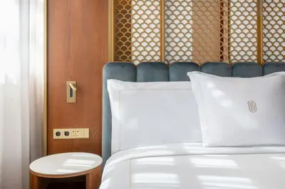 a bedroom with a white bed with a blue headboard at Grand Hotel Centenari, Valencia, Autograph Collection in Valencia