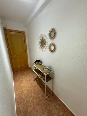 a hallway with a table and two mirrors on a wall at Apartamento amanecer paseo marítimo in Cullera