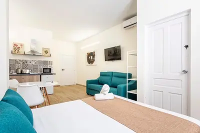 a bedroom with a blue couch and a kitchen at The Port Urban Loft in Valencia
