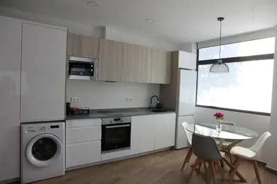 a kitchen with white cabinets and a table with chairs at Ruzafa Tropical in Valencia