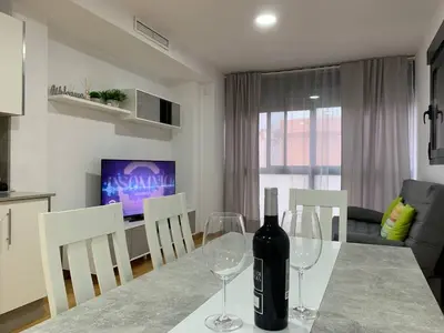 a dining table with two wine glasses on it at Sunrise Beach Apartment Playa Puerto de Sagunto in Puerto de Sagunto