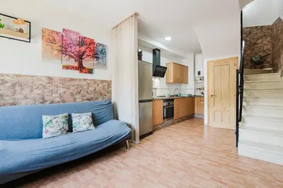 a living room with a blue couch and a kitchen at Casa Las 4 Estaciones in Caudiel