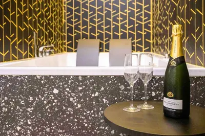 a bottle of champagne and two wine glasses on a table at Hotel Pathos by Mimood Aparthotels in Valencia
