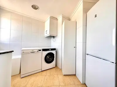 a white kitchen with a washing machine and a refrigerator at Vistas al mar, El Puig in El Puig