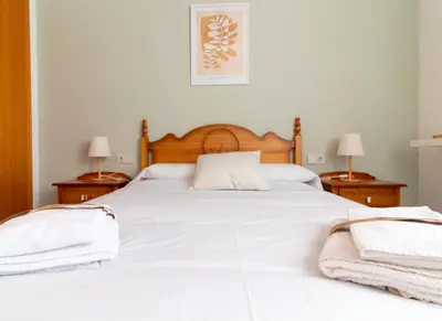 a bedroom with a large white bed with two lamps at Global Vacacional, Planta baja en Canet de Berenguer in Canet de Berenguer