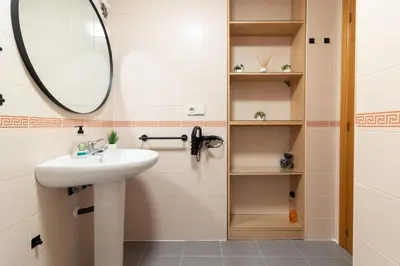 a bathroom with a sink and a mirror and shelves at Global Vacacional, Planta baja en Canet de Berenguer in Canet de Berenguer