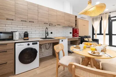 a kitchen and living room with a table and a dishwasher at Travel Habitat Nou Mestalla Suites in Valencia