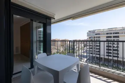 a white table and chairs on a balcony with a view at Apartamento con Vistas al mar, Piscina y Pista de Paddle in Valencia