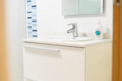 a white bathroom with a sink and a mirror at Apartamento con Vistas al mar, Piscina y Pista de Paddle in Valencia