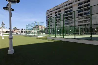 a large building with a green lawn in front of a building at Apartamento con Vistas al mar, Piscina y Pista de Paddle in Valencia