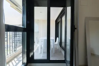 a room with a window with a table and chairs at Apartamento con Vistas al mar, Piscina y Pista de Paddle in Valencia