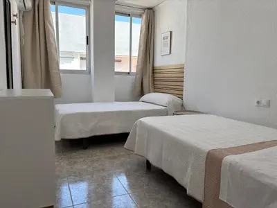 a hotel room with two beds and a window at VMC Rooms in Tavernes de Valldigna