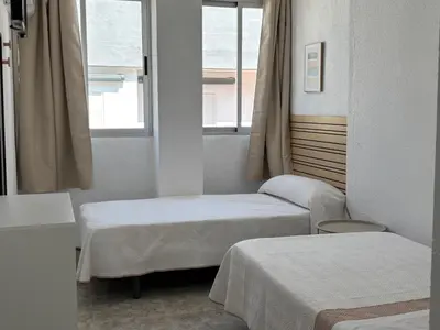 a room with two beds and two windows at VMC Rooms in Tavernes de Valldigna