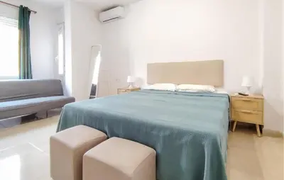 a bedroom with a bed with a blue blanket and two stools at Pet Friendly Home In Puerto De Sagunto in Puerto de Sagunto