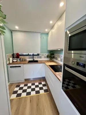a kitchen with white cabinets and a checkered floor at Casa Hoyo 19 in Masía Aldamar