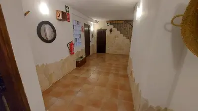 a hallway with a tile floor and a clock on the wall at Las Anas Rural in Cortez de Pallas