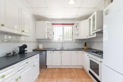 a white kitchen with white cabinets and black counter tops at Chalet Barraca d 'Aigües Vives in Barraca de Aguas Vivas